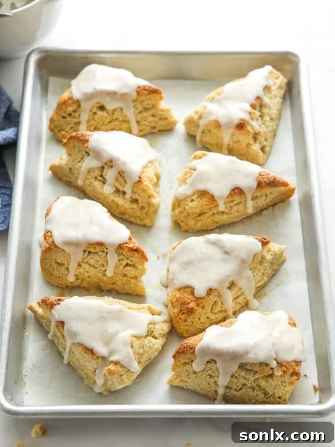 vanilla bean scones with frosting all on a baking sheet pan