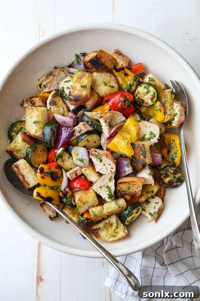 Grilled chicken and colorful vegetables for a fresh panzanella salad, showcasing summer ingredients.