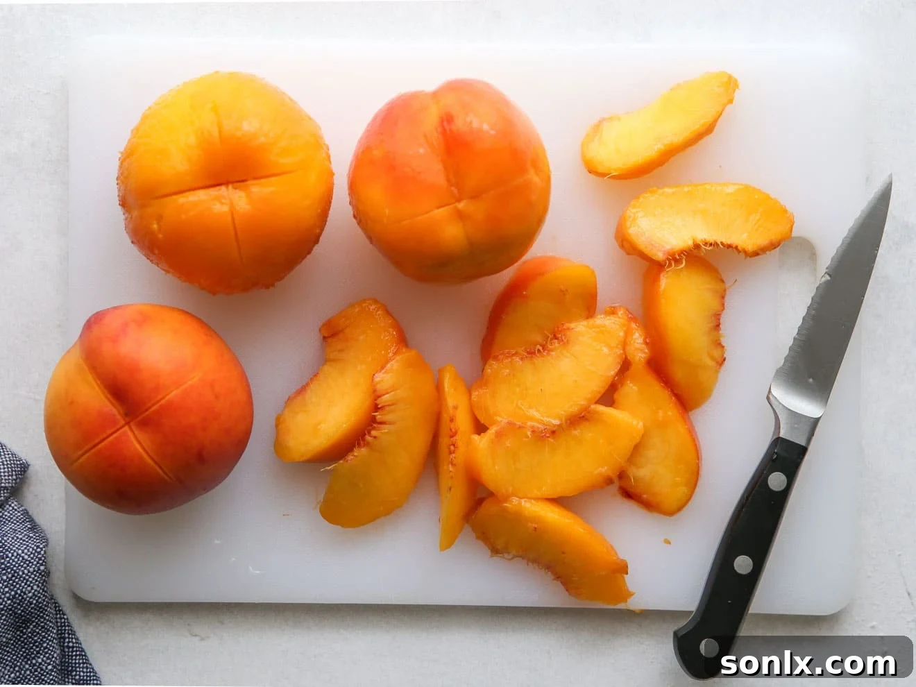 Hands carefully slicing peeled peaches, ready for the pie filling.