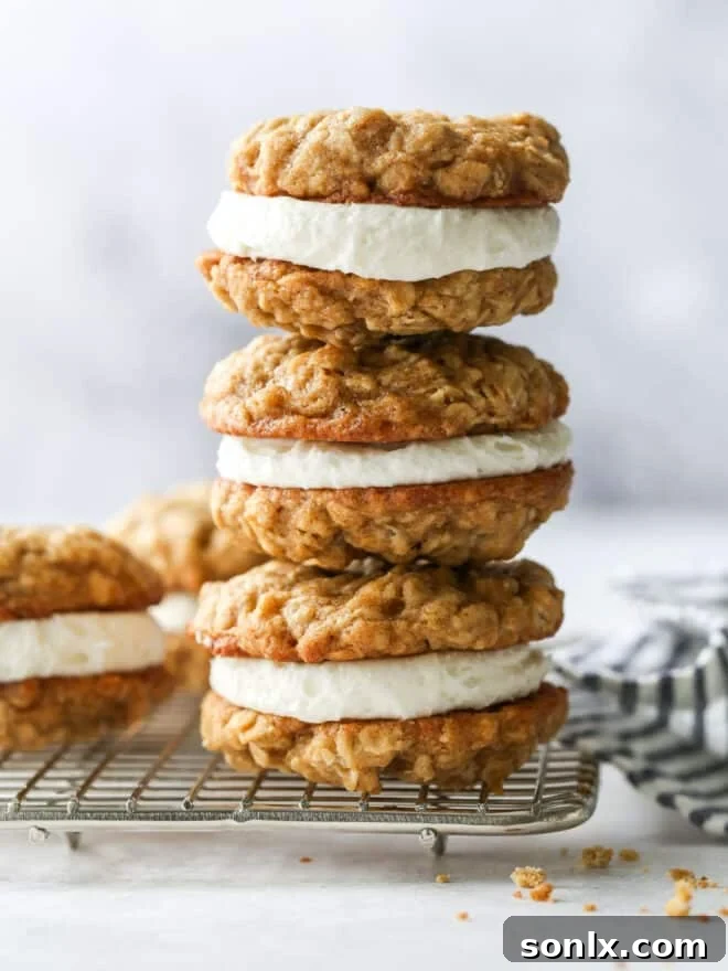 A stack of golden-brown oatmeal cream pie cookies resting on a wire rack, showcasing their soft texture and generous filling.