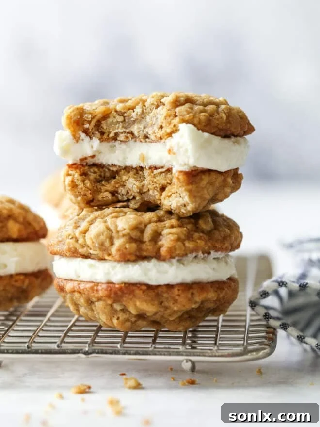 A small stack of oatmeal cream pie cookies, with one cookie showing a bite taken out, highlighting the soft cookie and creamy filling.