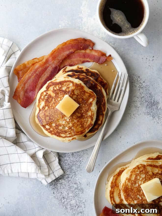 A final close-up of a stacked plate of golden, fluffy buttermilk pancakes, garnished with a few berries, highlighting their irresistible texture.