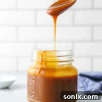 Homemade Caramel Sauce being poured into a jar.
