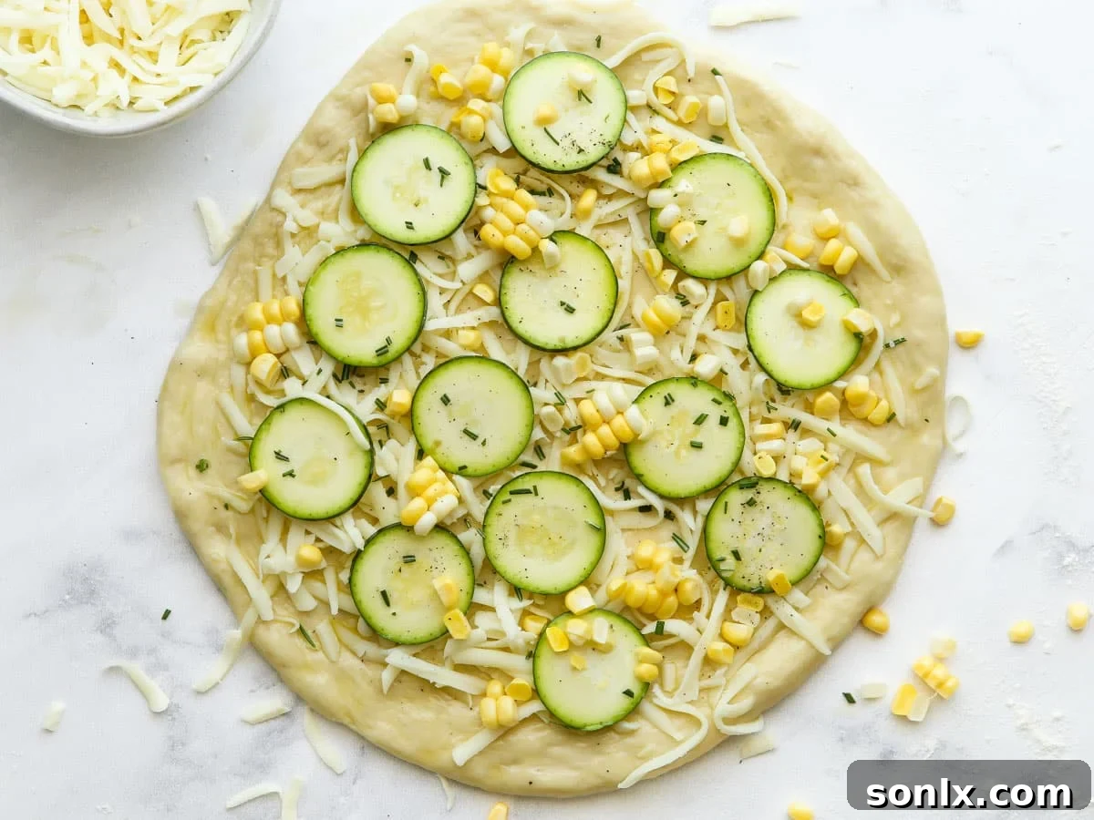Fully assembled zucchini corn pizza, topped with cheese, corn, zucchini, and herbs, ready to be transferred to the oven for baking