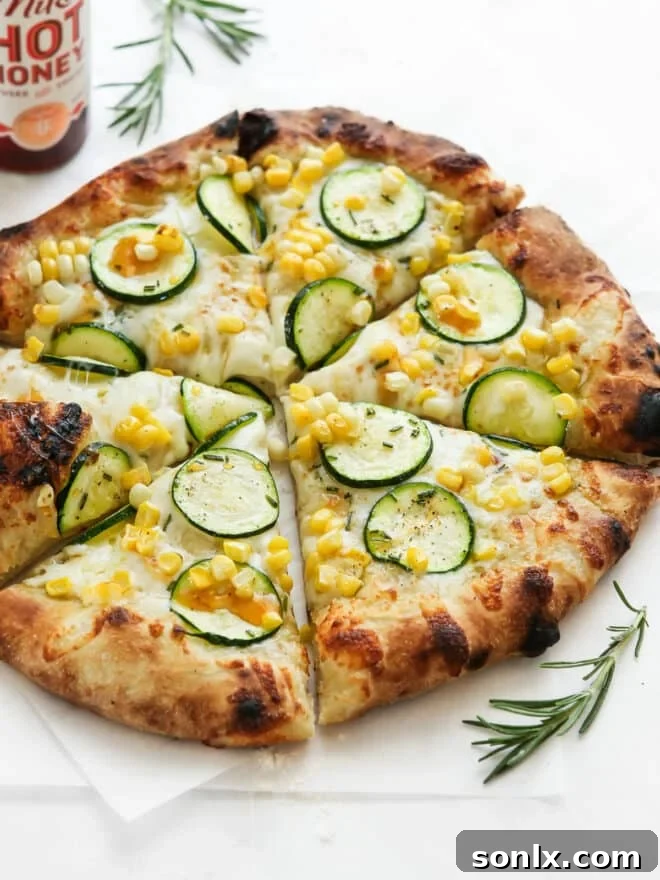 Close-up of freshly sliced zucchini corn pizza, revealing bubbling cheese and a perfectly baked crust, with a hot honey bottle in the background