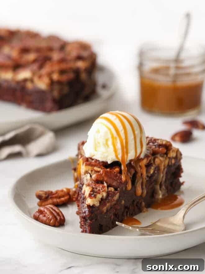A beautifully presented slice of pecan pie brownies, artfully topped with a generous scoop of vanilla ice cream and a luxurious caramel drizzle.