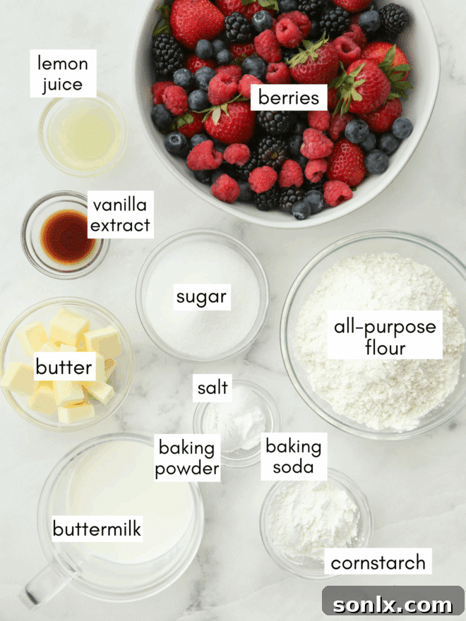 A collection of fresh ingredients for berry cobbler, including mixed berries, sugar, flour, butter, and buttermilk, neatly arranged on a counter.