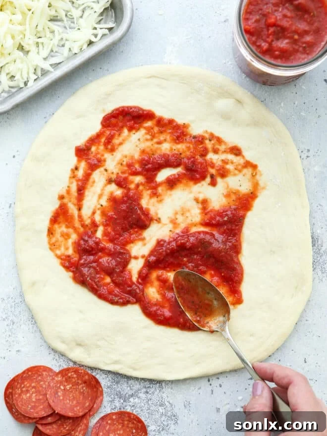 spreading pizza sauce on dough