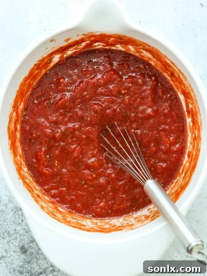 mixing pizza sauce in a big bowl with whisk