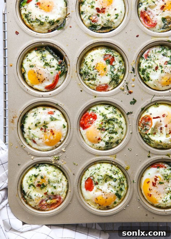 Close-up of baked egg cups with spinach, tomato, and parmesan cheese, perfect for breakfast meal prep.