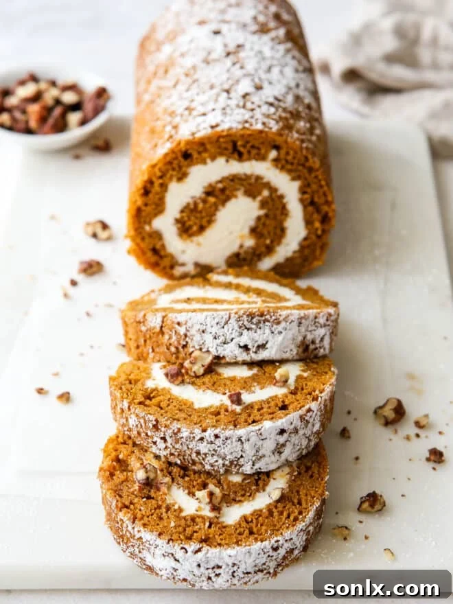 Whole pumpkin swiss roll cake garnished with powdered sugar and candied pecans, ready to be sliced.