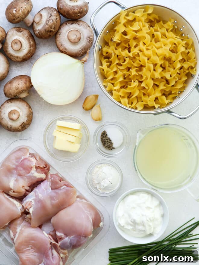 ingredients for chicken mushroom stroganoff laid out on a wooden board