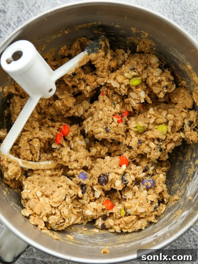 A bowl of freshly mixed Halloween monster cookie dough, vibrant with colorful candies and ready for baking