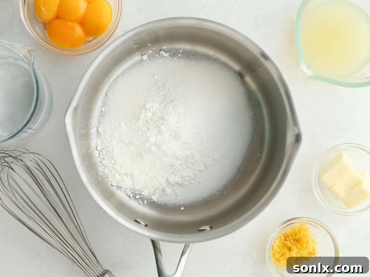 A saucepan on the stove filled with sugar and cornstarch, with other ingredients like lemons and eggs arranged neatly beside it.
