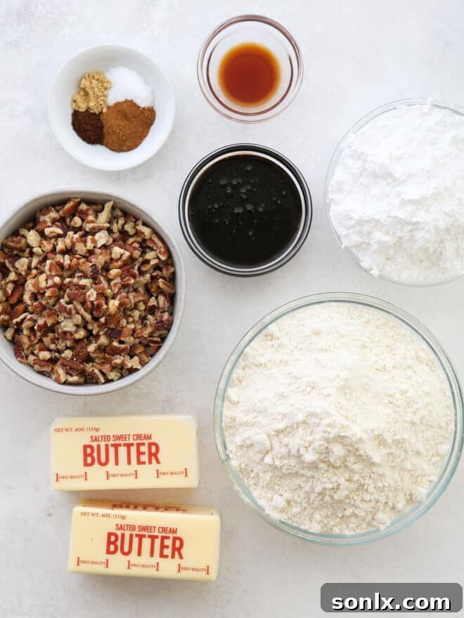 All the measured ingredients for Molasses Spice Snowball Cookies laid out on a white surface, including softened butter, powdered sugar, molasses, flour, a blend of spices, and finely chopped pecans, ready for baking.