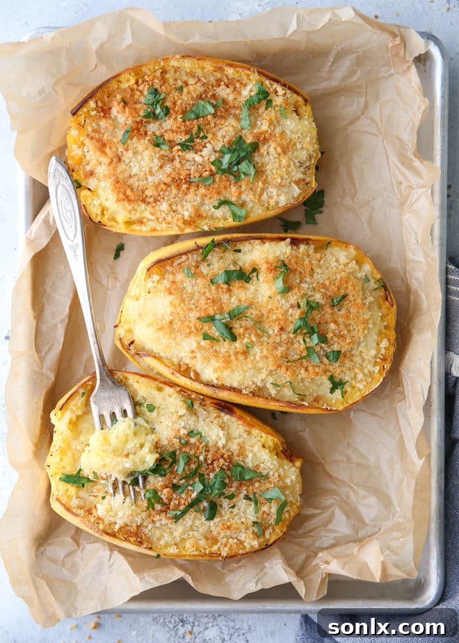 Spaghetti squash halves filled with cheesy mixture, topped with breadcrumbs and ready to bake