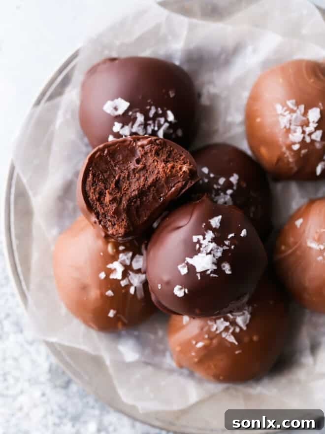 Indulgent chocolate truffle with a bite taken, resting elegantly on a pristine white plate, promising a moment of pure bliss.