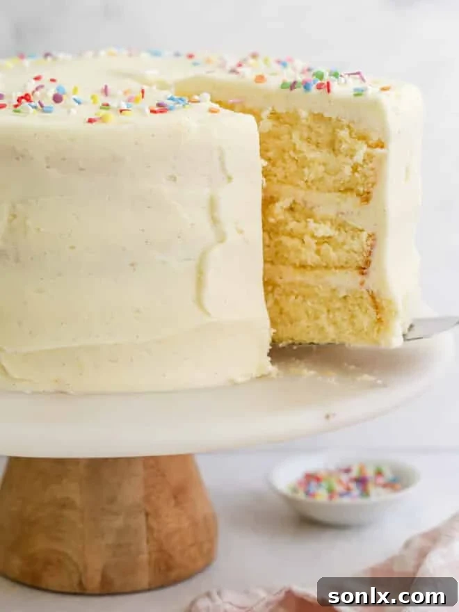A slice being taken out of a freshly baked vanilla layer cake