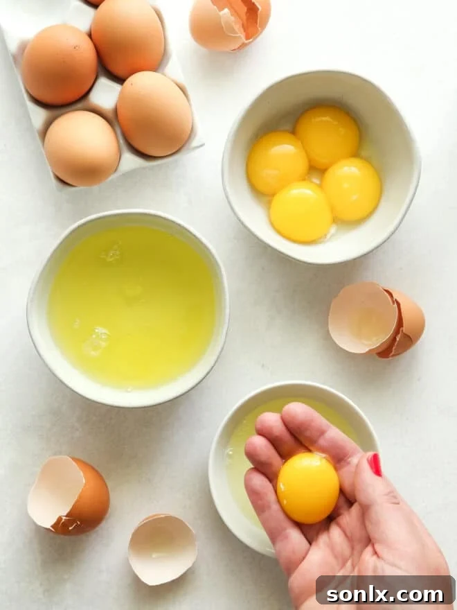 A close-up shot of hands carefully separating an egg yolk from the egg white, highlighting the delicate process in baking.