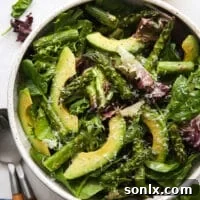 A vibrant roasted asparagus and avocado salad with lemon-parmesan vinaigrette in a bowl.