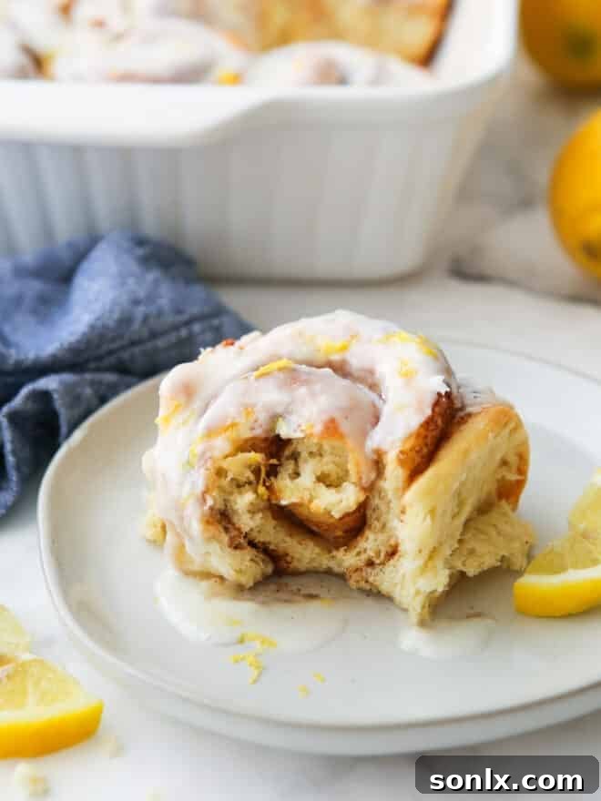 Close-up of a lemon cinnamon roll with a bite taken, revealing its soft, gooey, and zesty interior