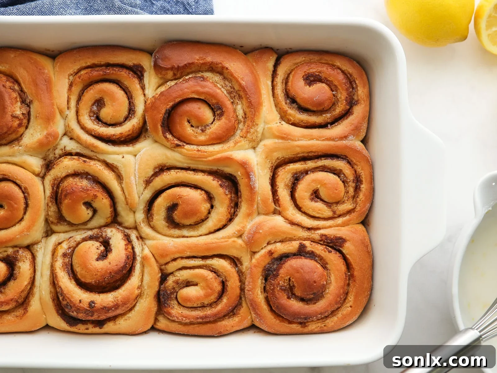 Freshly baked unfrosted cinnamon rolls in a rectangular baking pan, golden brown and ready for glaze