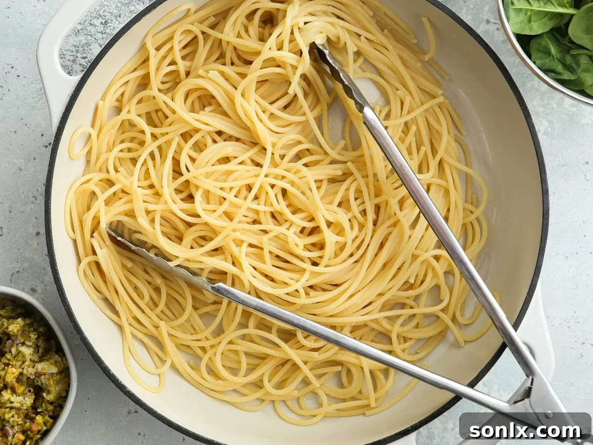 Boiled pasta in a pan, ready for the addition of spinach and lemon pistachio pesto.