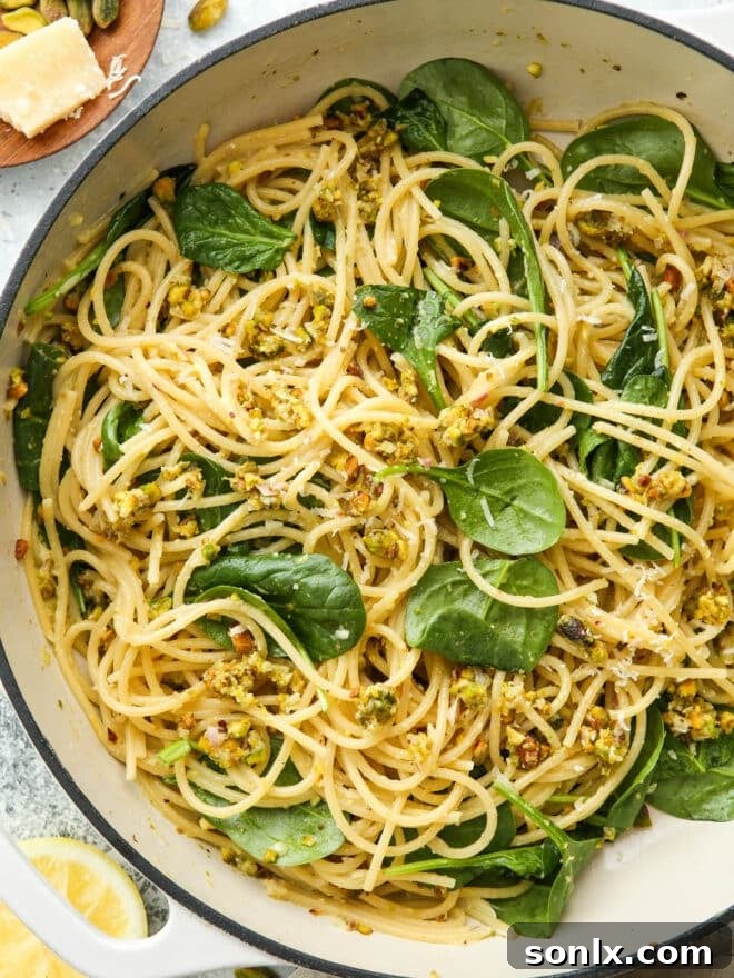 A close-up view of the finished lemon pistachio pasta with spinach in a cooking pan.