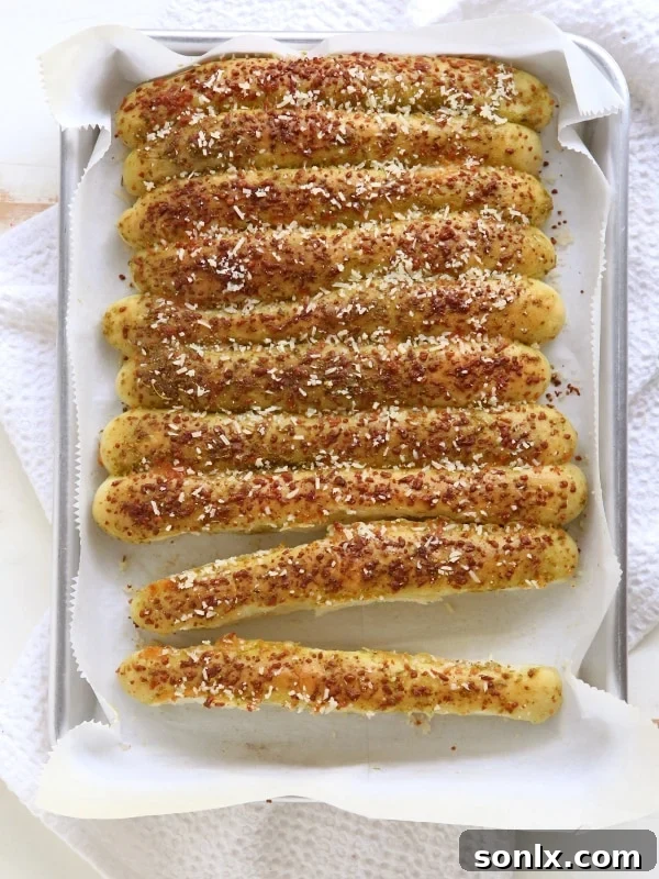 Hands rolling dough into breadstick shapes