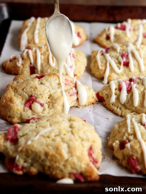 Several Rhubarb Vanilla Bean Scones arranged aesthetically on a rustic wooden surface, highlighting their homemade charm.