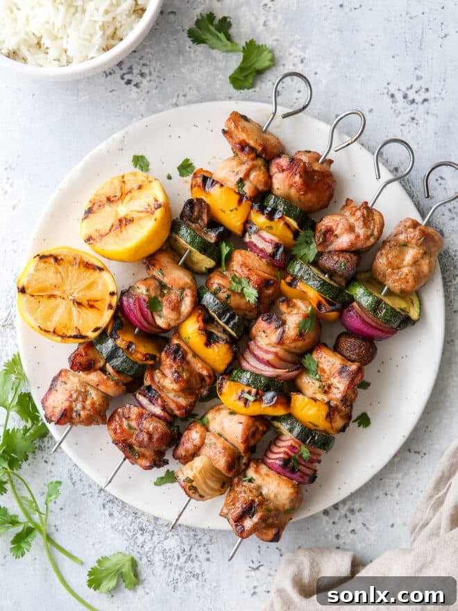 Delicious grilled lemon-cilantro chicken and veggie skewers served on a white plate with a garnish of fresh cilantro
