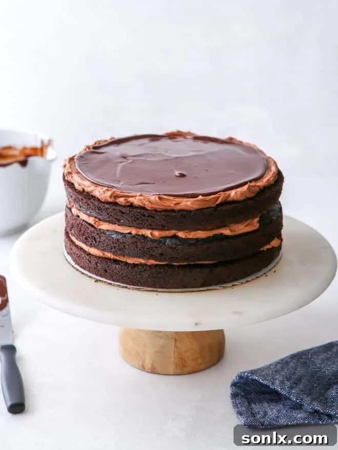 assembling chocolate fudge layer cake with layers of cake, frosting, and ganache