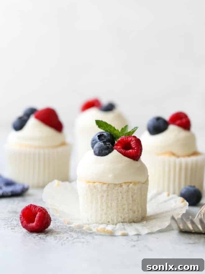 angel food cupcakes with whipped cream and fruit, one with wrapper turned down, showcasing a light, airy dessert