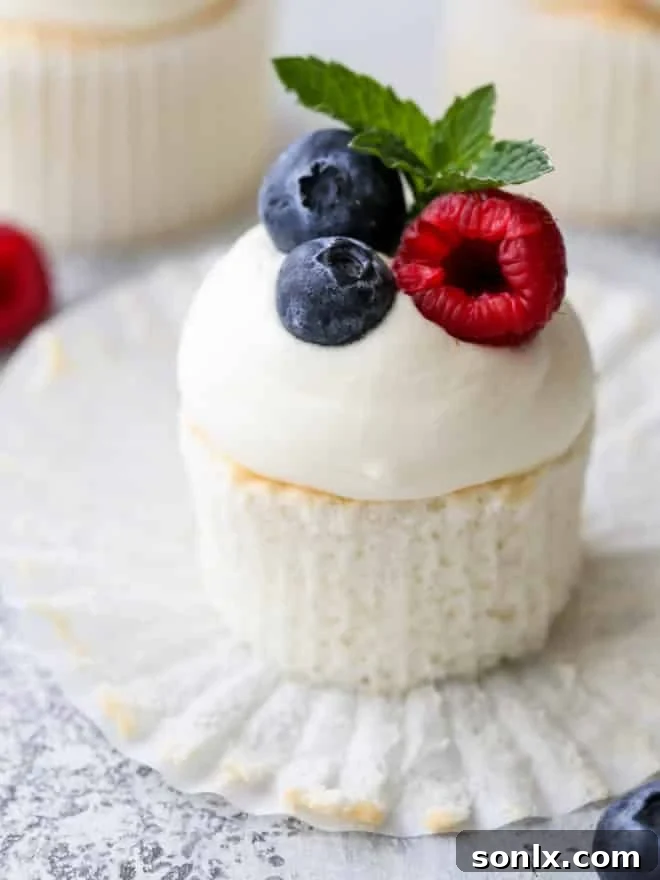 close-up view of delicate angel food cupcakes with whipped cream cheese buttercream and fresh raspberries