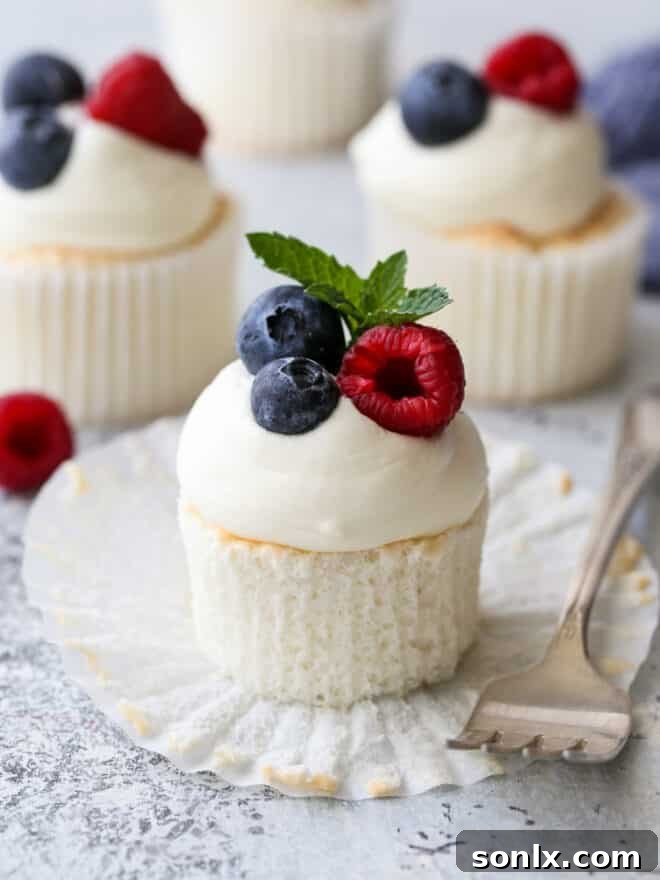 angel food cupcake on a white plate with a fork, showing its light texture