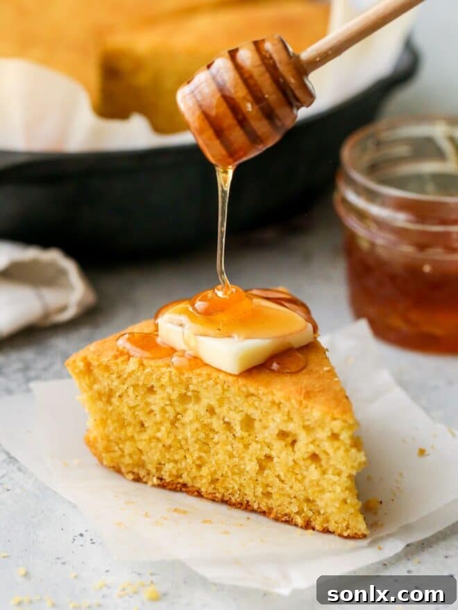 A delectable slice of honey buttermilk cornbread, warm and inviting, with honey drizzled over its golden surface.