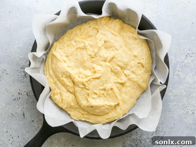 Thick honey buttermilk cornbread batter poured into a greased cast iron skillet, ready for baking.