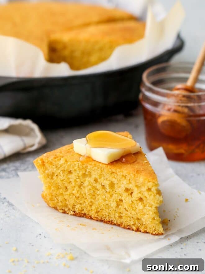 A close-up of a thick slice of golden honey buttermilk cornbread, showing its tender, fluffy texture.