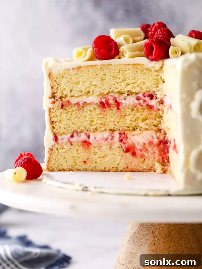 Sliced Raspberry White Chocolate Cake revealing perfect layers of yellow cake and creamy raspberry filling