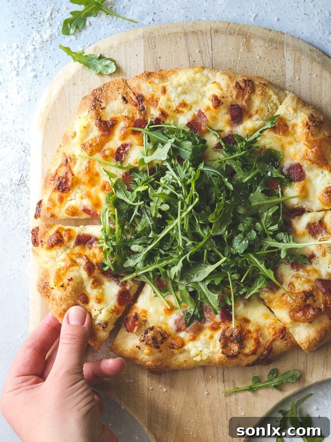 An irresistible three-cheese white pizza, enhanced with crispy bacon and fresh arugula for a delightful flavor profile.