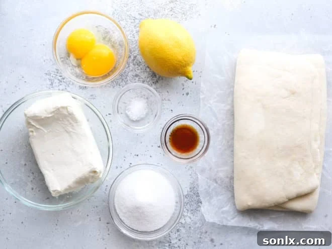 Ingredients for cream cheese Danishes laid out on a wooden board: puff pastry, cream cheese, sugar, egg yolks, vanilla, salt, lemon zest.