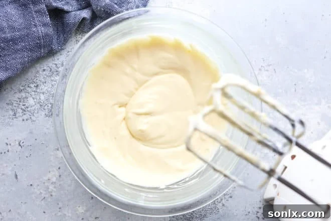 Close-up shot of a mixer blending cream cheese and other ingredients for the Danish filling until smooth and creamy.
