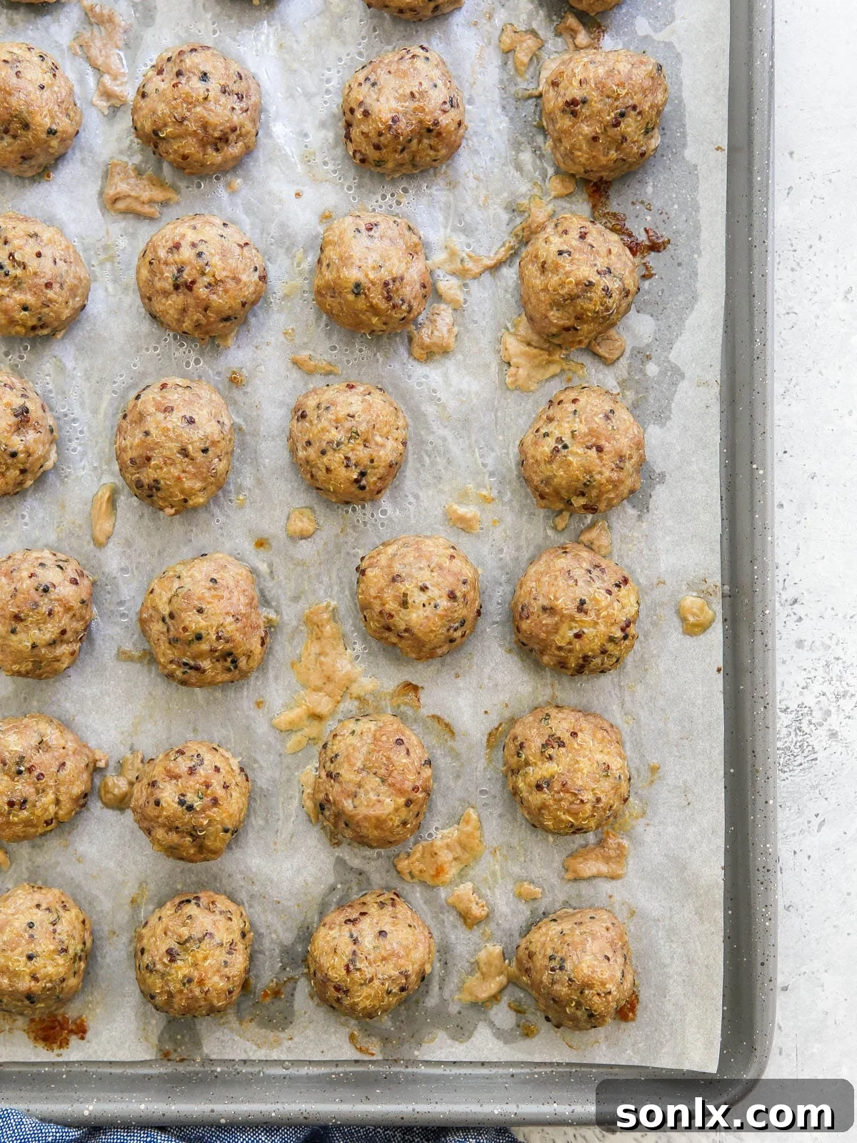 A tray of freshly baked pork quinoa meatballs, golden brown and perfectly cooked, just out of the oven.