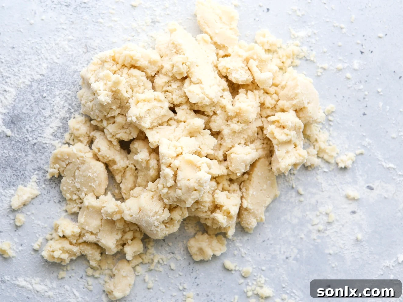 Crumbly pie dough emptied onto a clean work surface from the food processor.