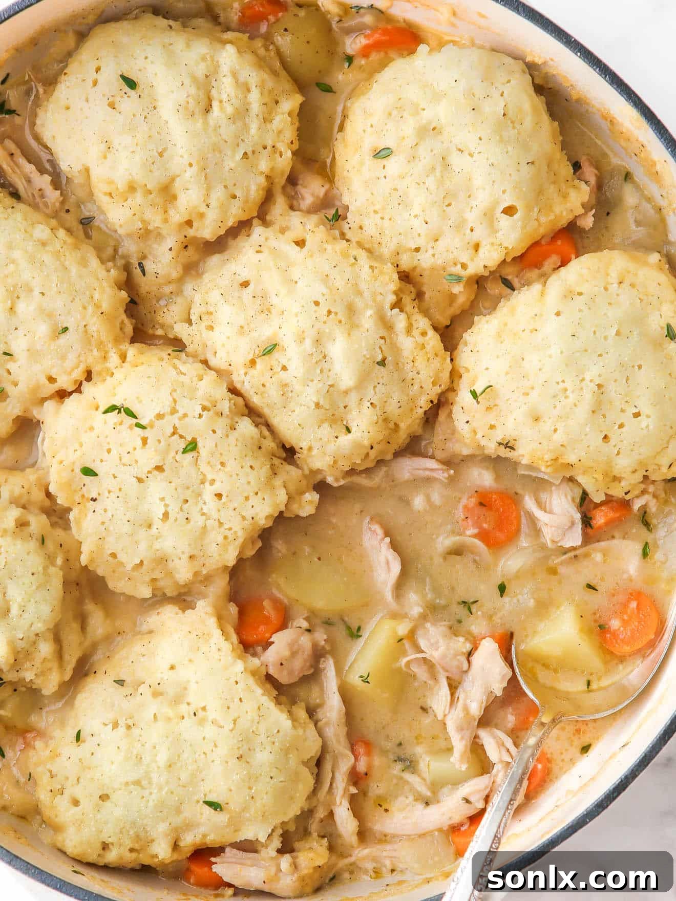 A close-up shot of fluffy buttermilk dumplings simmering atop turkey soup in a large pot, indicating they are almost ready.