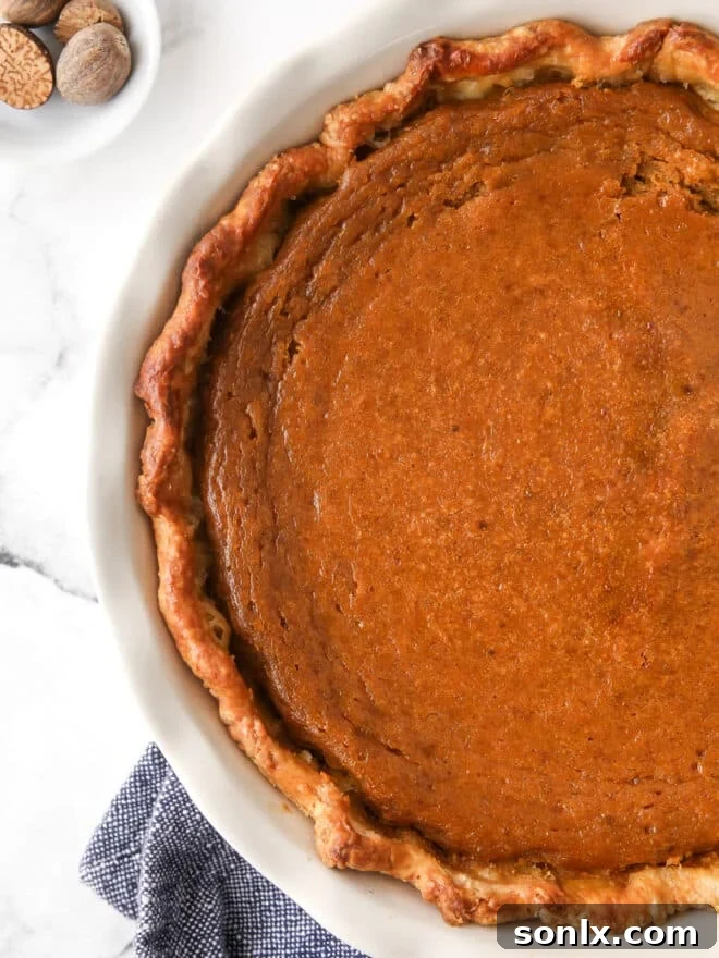 A whole classic pumpkin pie cooling on a wire rack, with a golden-brown crust and smooth filling.