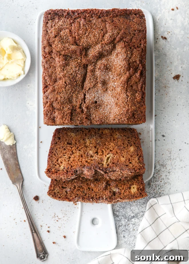 A freshly baked loaf of classic banana bread with a golden-brown cinnamon crumble topping, ready to be sliced and served.