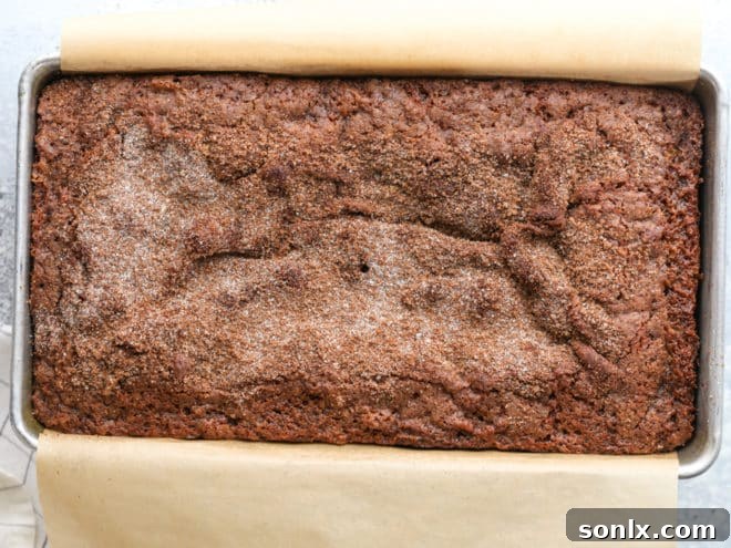 A slice of freshly baked cinnamon crumble banana bread with a cup of coffee on a rustic wooden board, ready to be enjoyed.