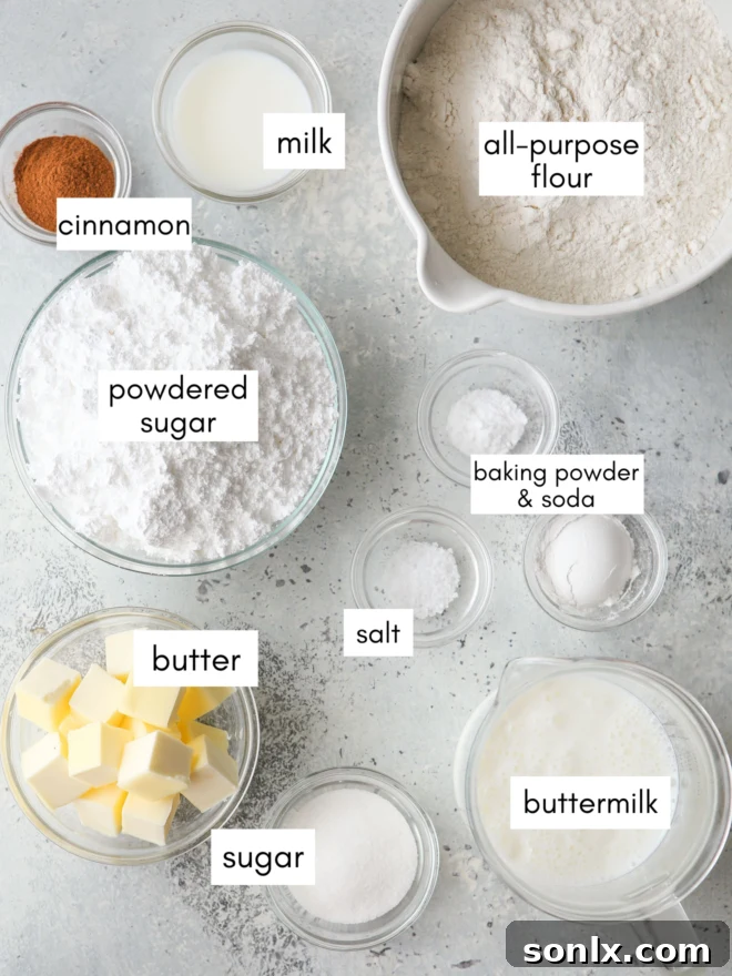 A flat lay photograph showcasing all the ingredients required for making cinnamon roll biscuits, including flour, butter, sugar, cinnamon, and buttermilk.