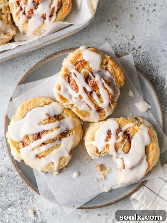 Two cinnamon roll biscuits with generous icing on a white plate, ready to be served.